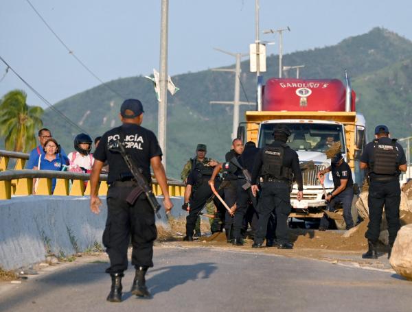 La policía municipal mueve los restos de un camión quemado y piedras que bloquean la carretera en el municipio de Coyuca de Benítez, estado de Guerrero, México, el 24 de octubre de 2024