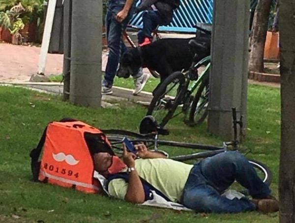 Este hombre duerme al lado de la maleta en donde transporta los alimentos.