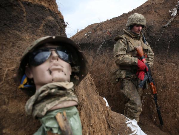 Un militar ucraniano camina en una trinchera junto a una especie de maniquí mientras se encuentra en su puesto en la línea del frente con Rusia.