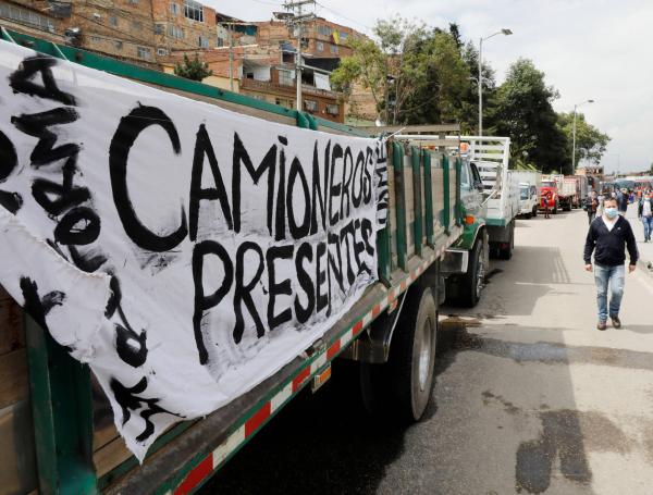 Decenas de personas tratan de llegar a sus destinos caminando por el bloqueo de vías realizado por conductores de camiones que participan de una nueva jornada de protesta. EFE/ Carlos Ortega