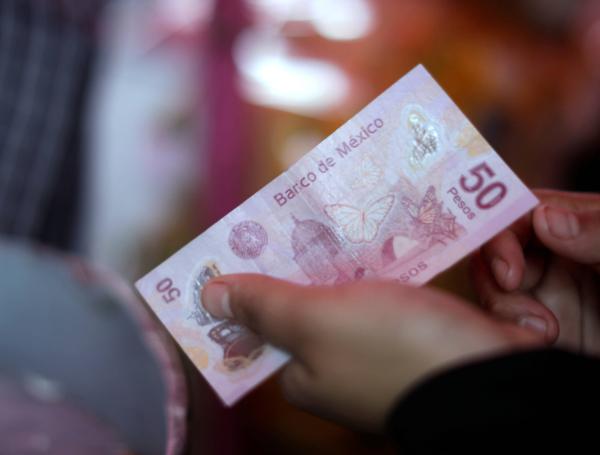 Un vendedor sostiene un billete en un mercado al aire libre en la Ciudad de México