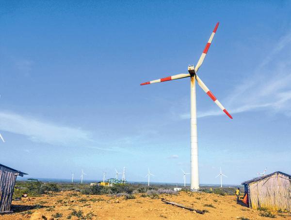 Molino de viento moderno, en medio de casas indígenas wayú, en el desierto de La Guajira.