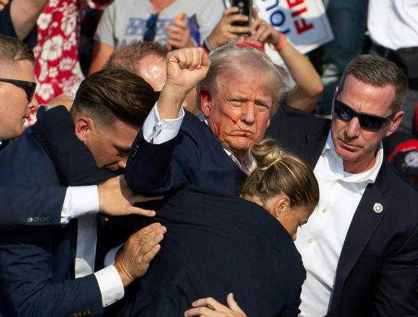 El candidato republicano Donald Trump es visto con sangre en la cara tras un tiroteo en un mitin de su campaña.