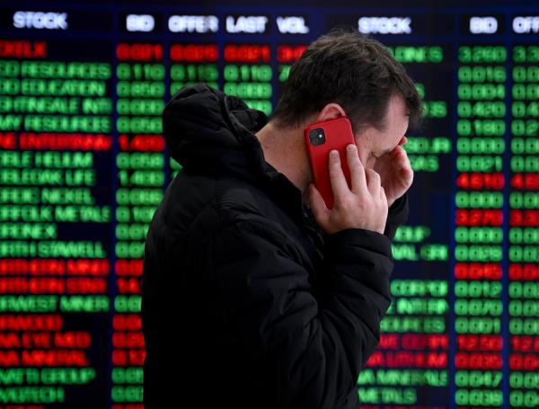 Una persona habla por teléfono frente a los paneles indicadores en la Bolsa de Valores de Australia (ASX) en Sídney, Australia, este lunes.