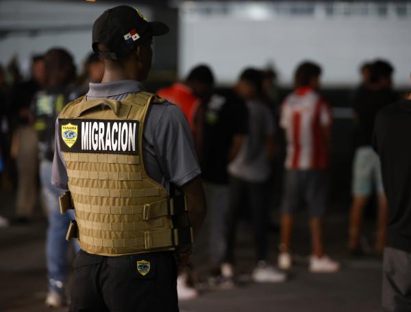 Un agente de migración de Panamá vigila a migrantes luego de ser deportados de los Estados Unidos este martes, en el aeropuerto Marcos A. Gelabert en Ciudad de Panamá (Panamá). Un primer grupo de migrantes, que cruzó el Darién ilegalmente, regresó al país centroamericano de acuerdo a un memorando de entendimiento entre los gobiernos de Panamá y los Estados Unidos.