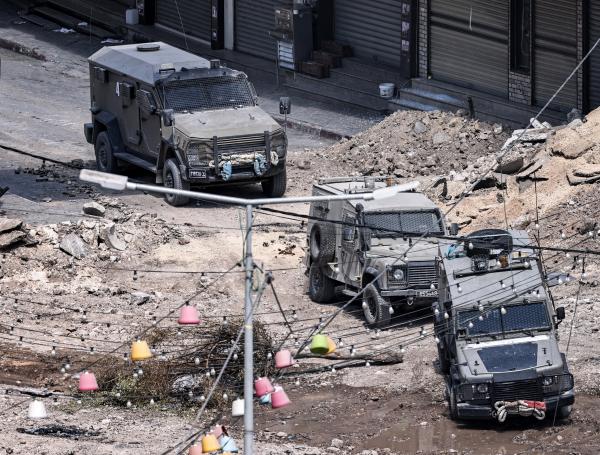 Vehículos blindados del ejército israelí avanzan por un tramo excavado de una carretera en el centro de Yenín, en Cisjordania.