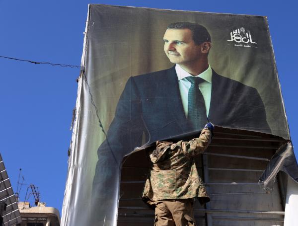 Rebeldes arranca un retrato del presidente sirio Bashar al-Asad en Alepo.