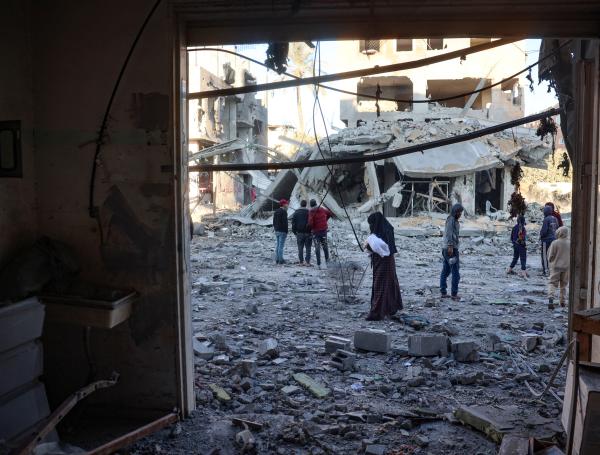 Palestinos caminan frente a un edificio destruido en un ataque aéreo israelí en Nuseirat.