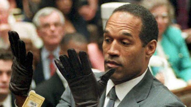 O.J. Simpson mira los guantes que se midió ante la Corte.