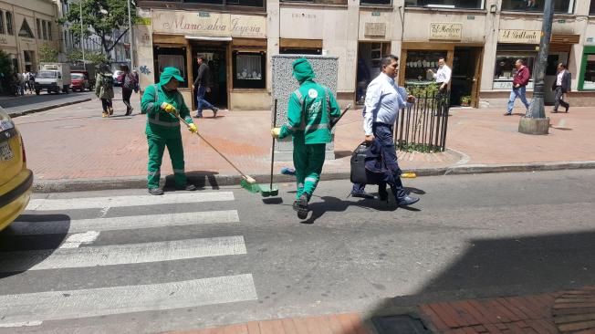 En medio de la protesta por su inminente salida de la empresa Aguas de Bogotá, estos trabajadores, como muchos otros, siguieron adelante con su labor de aseo de la ciudad.