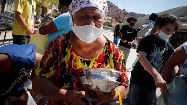 En Paraisópolis, una de las mayores favelas de Sao Paulo, el hambre golpea con fuerza la puerta de miles de familias que reciben donaciones, en la avenida Paulista, en Sao Paulo (Brasil). Un año después del comienzo de la pandemia, las muertes y los casos de covid-19 escalan día a día en Brasil, pero las ayudas para los más pobres no paran de caer.