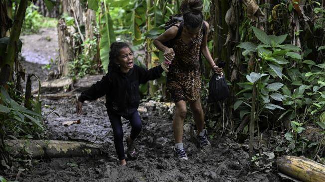 Migrante venezolana ayuda a su hija mientras cruzan la selva del Darién