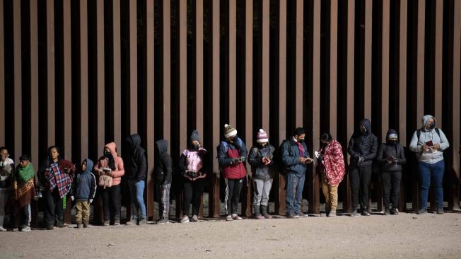 Solicitantes de asilo hacen fila para ser procesados por agentes de la Patrulla Fronteriza y Aduanas de Estados Unidos.