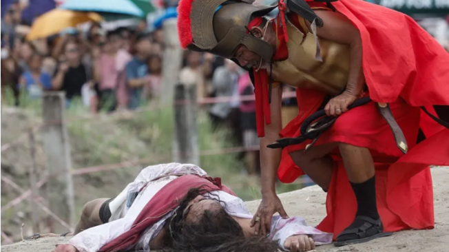 El filipino Rubén Enaje (i), que interpreta a Jesucristo, recrea escenas de la crucifixión y muerte.