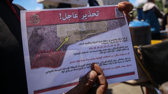 Un palestino muestra un folleto lanzado por un avión israelí advirtiéndoles que evacuen antes de las operaciones militares en Rafah, Gaza.