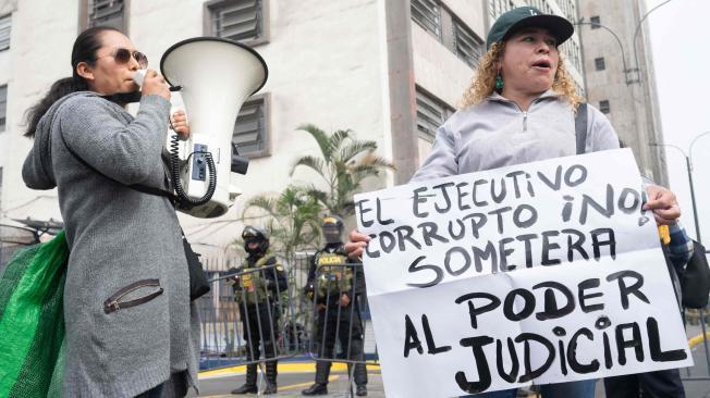 Opositores de la presidenta peruana Dina Boluarte sostienen carteles y gritan mientras ella comparece ante la Fiscalía Nacional en Lima el 15 de mayo de 2024, citada para dar un nuevo testimonio en el marco de la investigación denominada "Rolexgate".