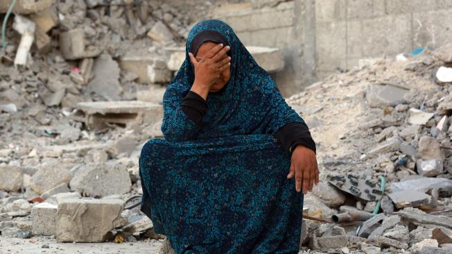 Una mujer palestina hace gestos sentada sobre los escombros de bombardeos israelíes anteriores, en Jan Yunis, en el sur de la Franja de Gaza.