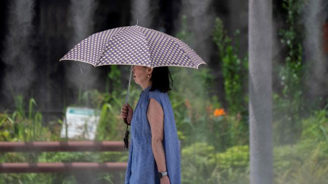 Una mujer pasa junto a una ducha de niebla durante un clima cálido en el centro de Tokio el 9 de julio de 2024.