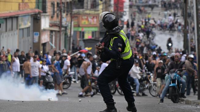 Policía antidisturbios utiliza gases lacrimógenos contra manifestantes durante una protesta en el barrio de Catia, en Caracas.