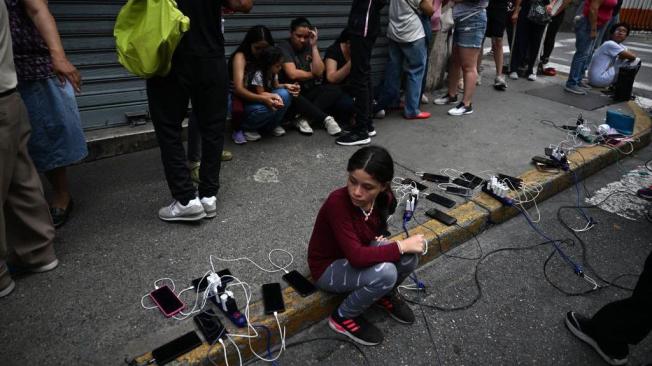 Decenas de venezolanos se acercaron al camión del municipio de Chacao para cargar sus celulares durante un apagón en Caracas de este viernes.