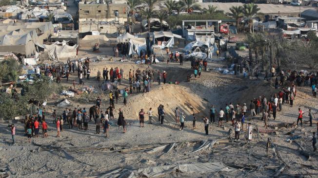 Los palestinos inspeccionan el daño en el lugar de los ataques israelíes en un campamento improvisado para desplazados en Mawasi, Jan Yunis.