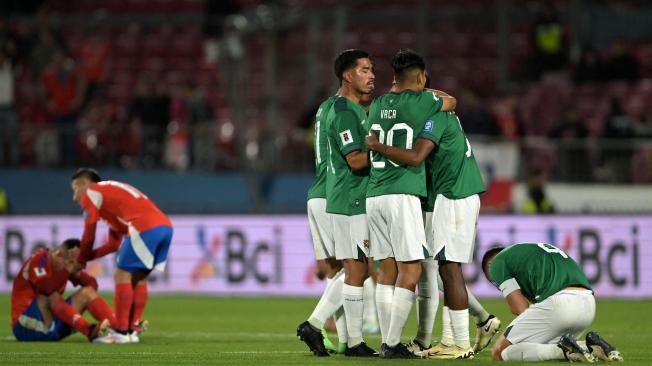 TOPSHOT - Players of Bolivia celebrate after winning the 2026 FIFA World Cup South American qualifiers football match between Chile and Bolivia, at the National stadium in Santiago, on September 10, 2024. (Photo by Rodrigo ARANGUA / AFP)