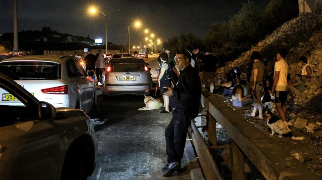 Varias personas se protegen junto a vehículos bajo un puente en una carretera entre Kafr Qara y Baqa al-Gharbiya, en el norte de Israel.