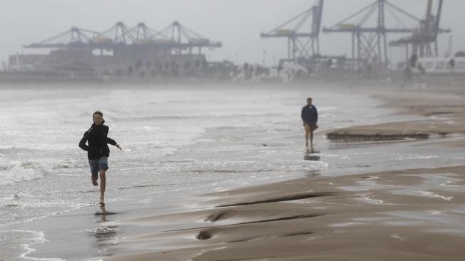 GRAFCVA3789. VALENCIA, 29/10/2024.- Dos personas pasean por la playa de la Malvarrosa durante este martes en el que las lluvias torrenciales afectan a la Comunitat Valenciana, especialmente a la provincia de Valencia, en la que se ha establecido el aviso rojo y han obligado a cerrar el puerto de Valencia y el de Sagunto. EFE/Biel Aliño