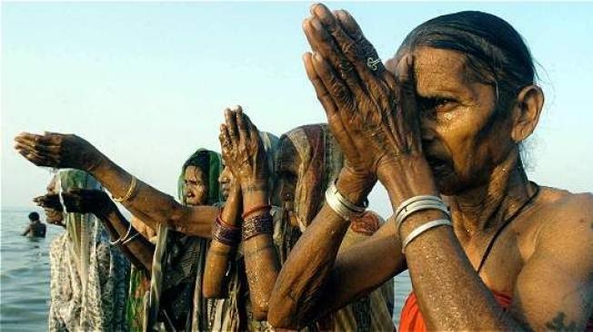 Peregrinos elevan sus oraciones mientras toman un baño ritual en isla de Gangasagar, de la bahía de Bengala, a unos 140 km de Calcuta.