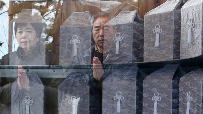 Dos personas rezan frente a los restos de varias víctimas de la tragedia de Fukusima en la ciudad de Otsuchi.