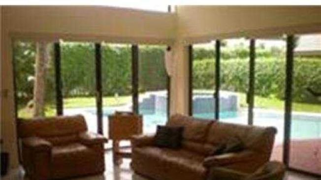 Uno de los cuartos y la sala de la casa a nombre de Rodrigo Prieto en Boca Ratón, Florida cuentan con vista al jardín y a la piscina.