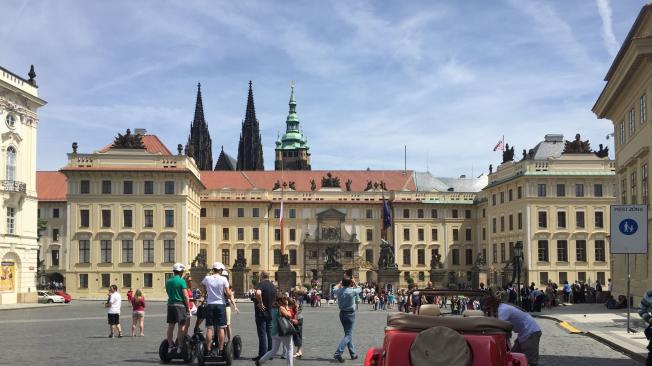 Un vehículo clásico checo y, al fondo, la entrada al Castillo de Praga. Y más al fondo se asoman las torres de la catedral de San Vito.