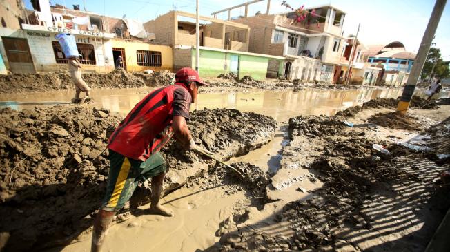 Residentes limpian una calle inundada después de que los ríos rompieron sus riberas debido a las lluvias torrenciales, causando inundaciones y destrucción generalizada en Huarmey, Ancash, Perú.