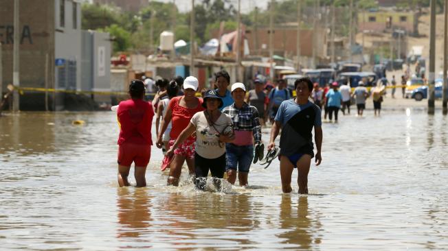 Los residentes atraviesan una calle inundada en Huarmey, Ancash, Perú.