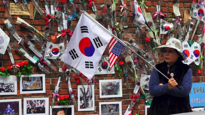 Una partidaria de la ex presidenta de Corea del Sur, Park Geun-Hye, se encuentra frente a una pared con rosas y fotografías de Park en Seúl.