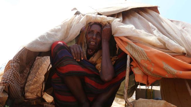 Una mujer desplazada descansa fuera de su refugio. La somalí debió migrar debido a la sequía y hambruna extrema en zonas como Baidoa, cerca de la capital de Somalia.