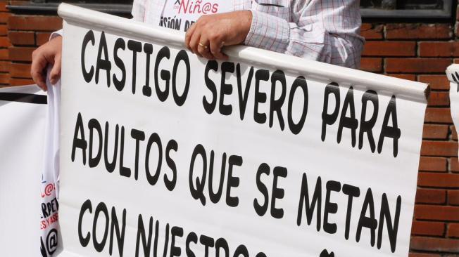 Afuera de las instalaciones de Paloquemao también permanece un grupo de personas que con pancartas y pitos piden la condena máxima contra Uribe.