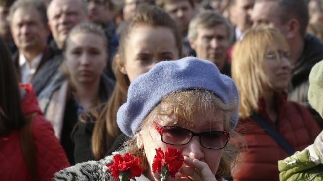 Una mujer sostiene dos flores durante una marcha en memoria de las víctimas del atentado del lunes en el metro de San Petersburgo.
