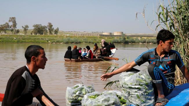 Los iraquíes desplazados de Mosul cruzan el Tigris en barco desde la aldea de Thibaniya, al sur de la ciudad.