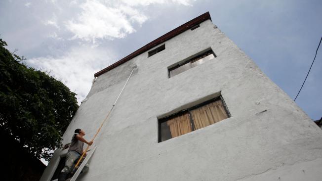 Mejía pinta con un rodillo la fachada de la casa de Yepes.