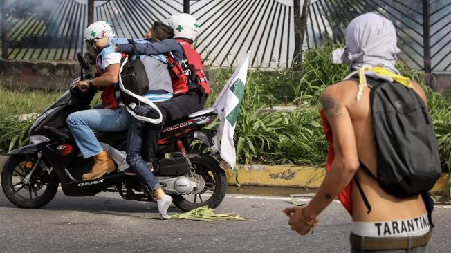 Dos manifestantes llevan en una motocicleta al joven David José Vallenilla (2i), de 22 años, luego de recibir un disparo en las inmediaciones de la bases aérea militar La Carlota, en Caracas.