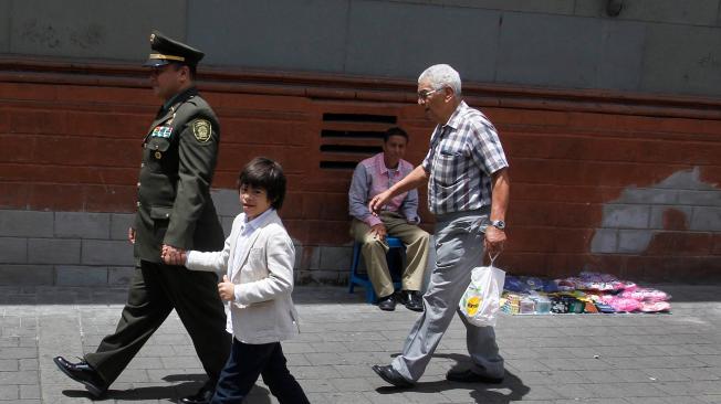 Édison va vestido con su uniforme de policía y con orgullo lleva de la mano a Isaac por las calles del centro de Medellín.