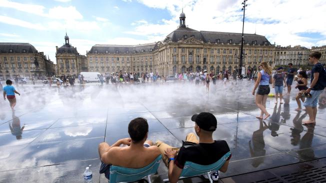 Un grupo de personas se refrescan en la fuente Miroir d'eau en el centro de Burdeos (Francia).