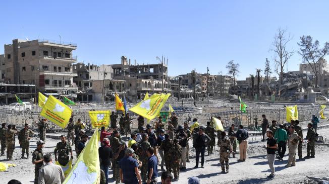 Miembros de las Fuerzas Democráticas Sirias (FDS) elevan sus banderas para festejar la liberación de Al Raqa.