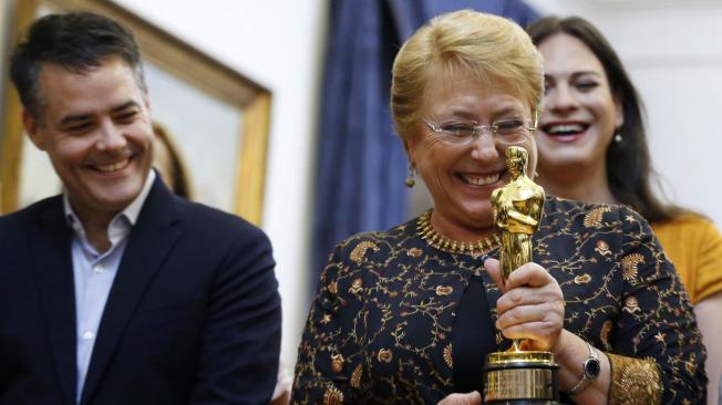 La presidenta de Chile, Michelle Bachelet, sostiene el premio Óscar, al lado de los ganadores.