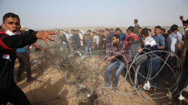 Manifestantes intentan derribar una cerca de alambre en la frontera.