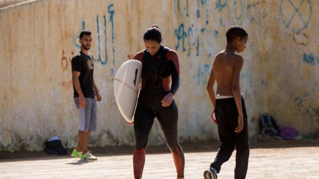 Rim, una surfista de Marruecos, camina por la playa después de una sesión de práctica.