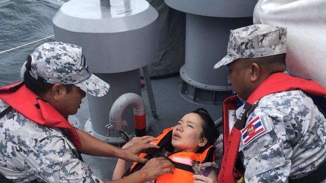 Efectivos de la Marina ayudan a una de las turistas rescatadas durante las labores de rescate de las víctimas de un naufragio frente a la costa de Phuket (Tailandia).