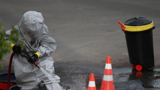 Un bombero limpia su uniforme tras procedimiento por presencia de químicos en Cali.