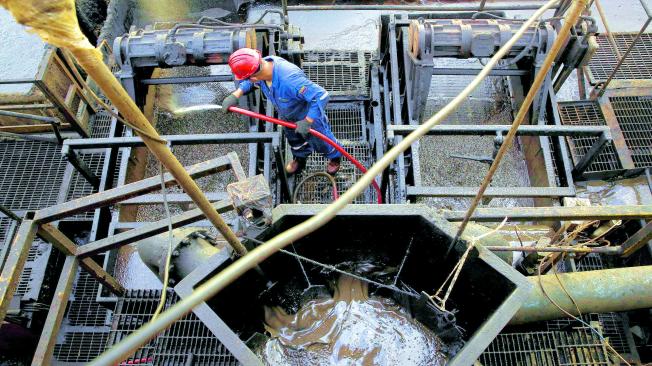 El flujo de petróleo crudo se ve en un contenedor mientras un trabajador petrolero trabaja en el campo petrolero de Venezuela PDVSA, cerca de Cabrutica.